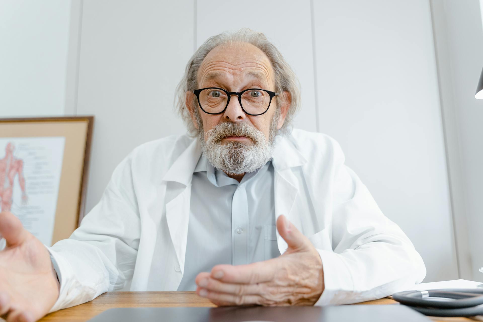 A senior male doctor in a professional telemedicine consultation setting.