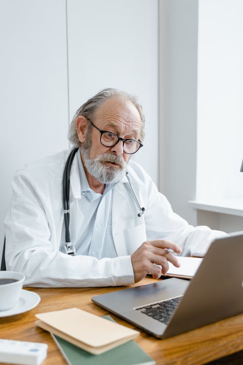 A Man Wearing Eyeglasses While Using Laptop