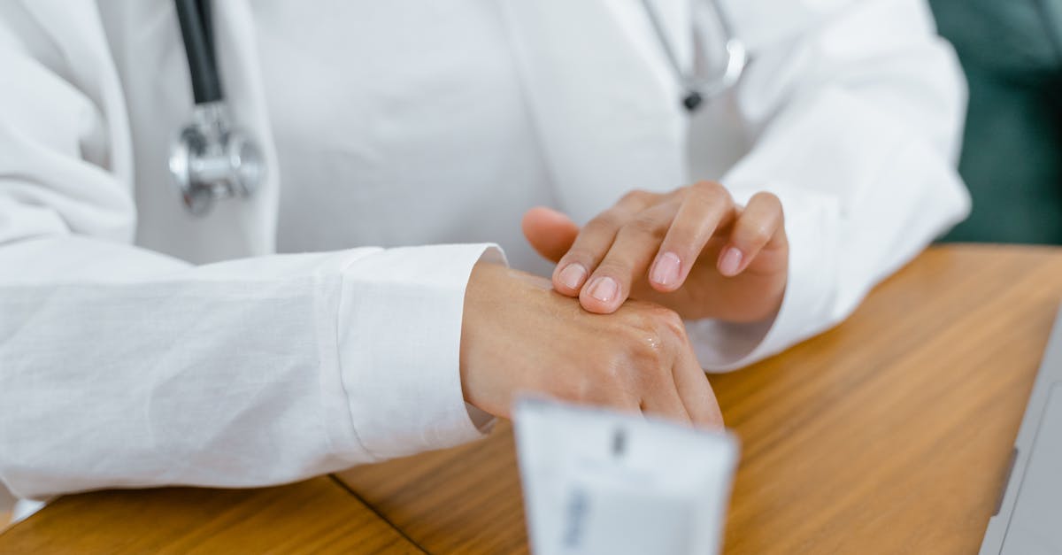 Photo by Tima Miroshnichenko A healthcare professional in a white coat applying cream on hand, emphasizing treatment and care.