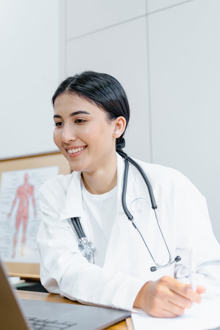 A Smiling Doctor In White Lab Coat With Stethoscope On Her Neck