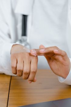 Close-up of a doctor applying cream to their hand, emphasizing telemedicine and healthcare.