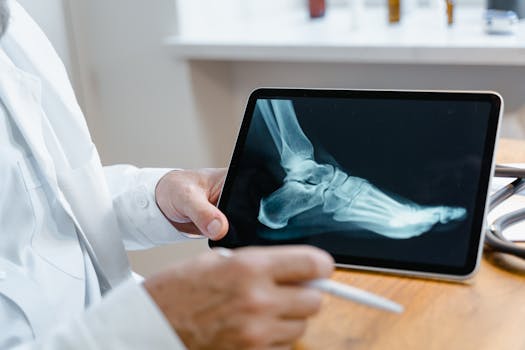 Doctor examining a foot X-ray image on a digital tablet using a stylus in a medical office.
