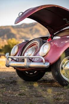 Close-up of a vintage Volkswagen Beetle with hood open on a dirt road, perfect classic car theme.