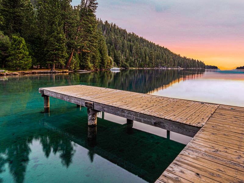 Wooden pier on a forested lake at sunset