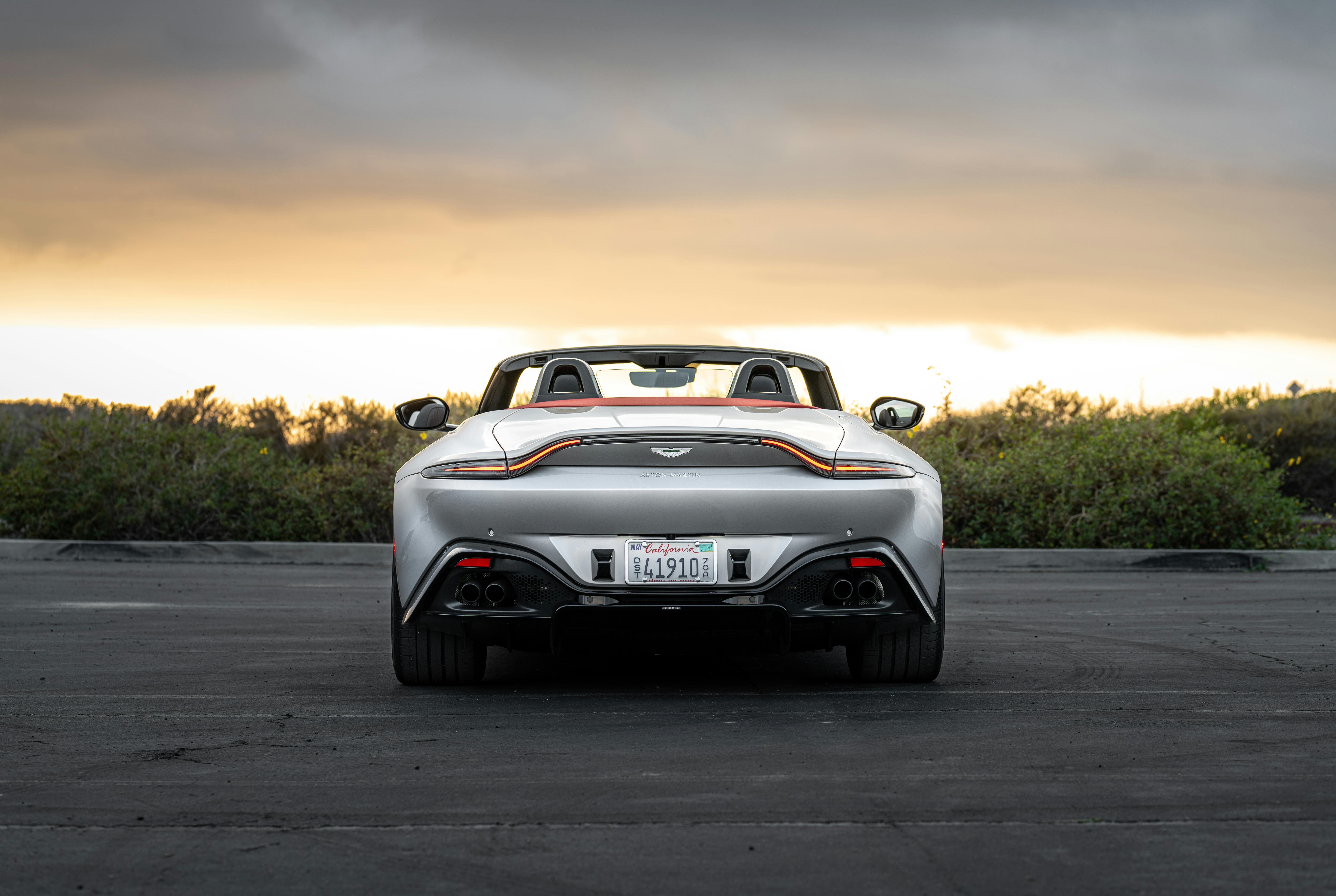 Rear view of a luxury convertible sports car parked outdoors at sunset.