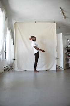 A man poses confidently in a minimalist indoor studio with a white background.