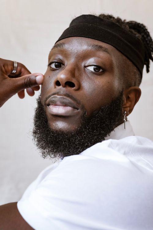 Free A striking portrait of a black man with a beard and headband, captured in a studio setting. Stock Photo