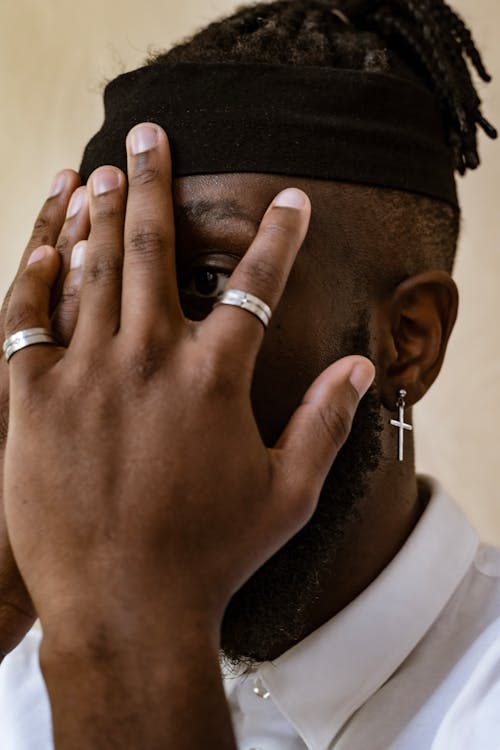 A Man Covering His Face Using His Hands with Silver Rings