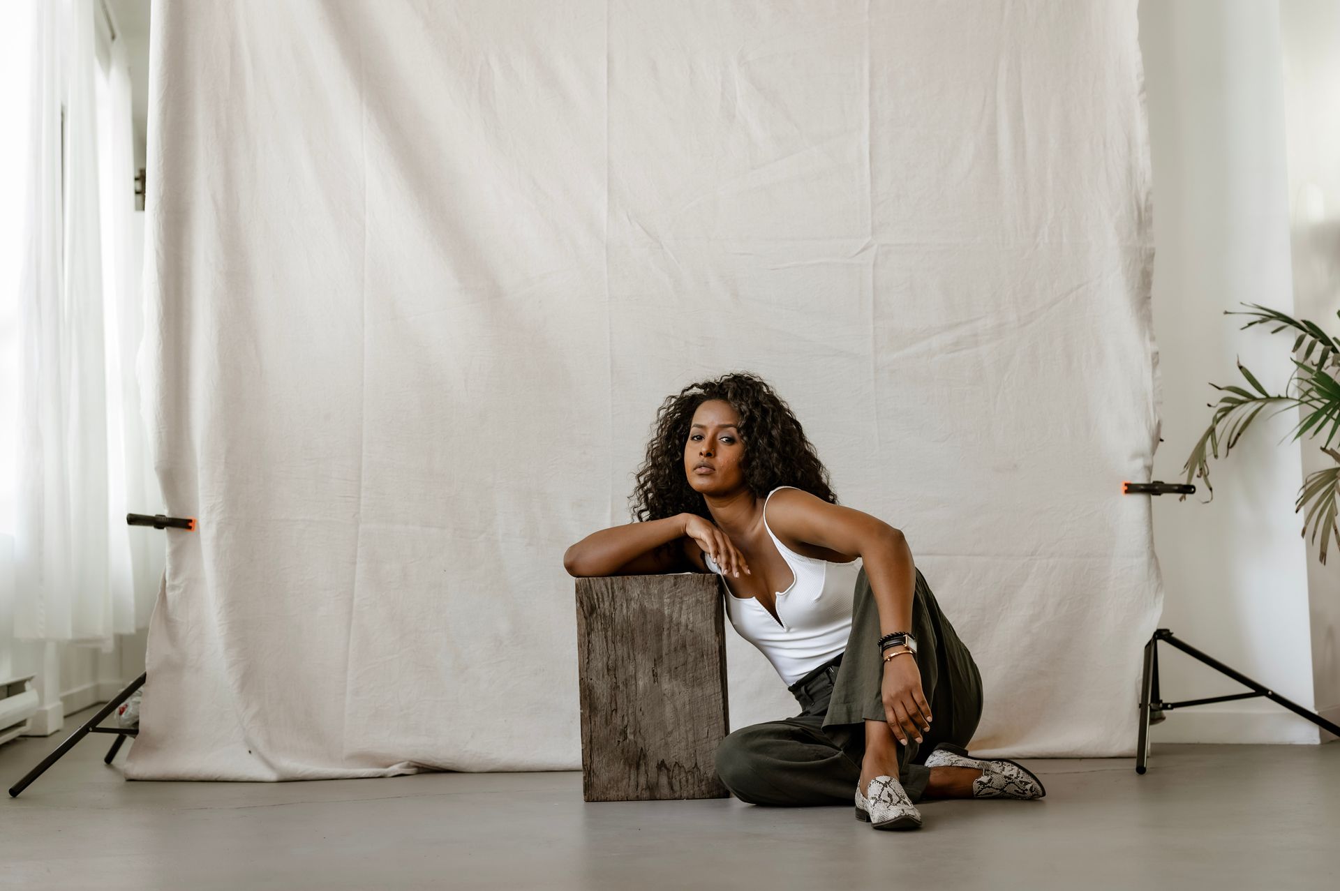 African American woman posing stylishly in a studio setting with relaxed elegance.