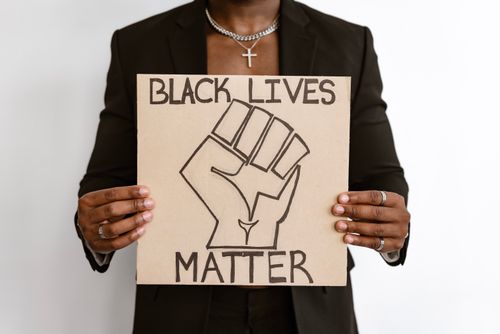 Free A person holding a Black Lives Matter sign with raised fist symbol, emphasizing equality. Stock Photo
