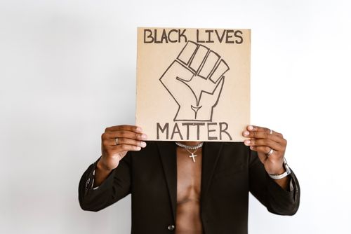 Free A person holding a Black Lives Matter placard with a fist symbol on a white background. Stock Photo