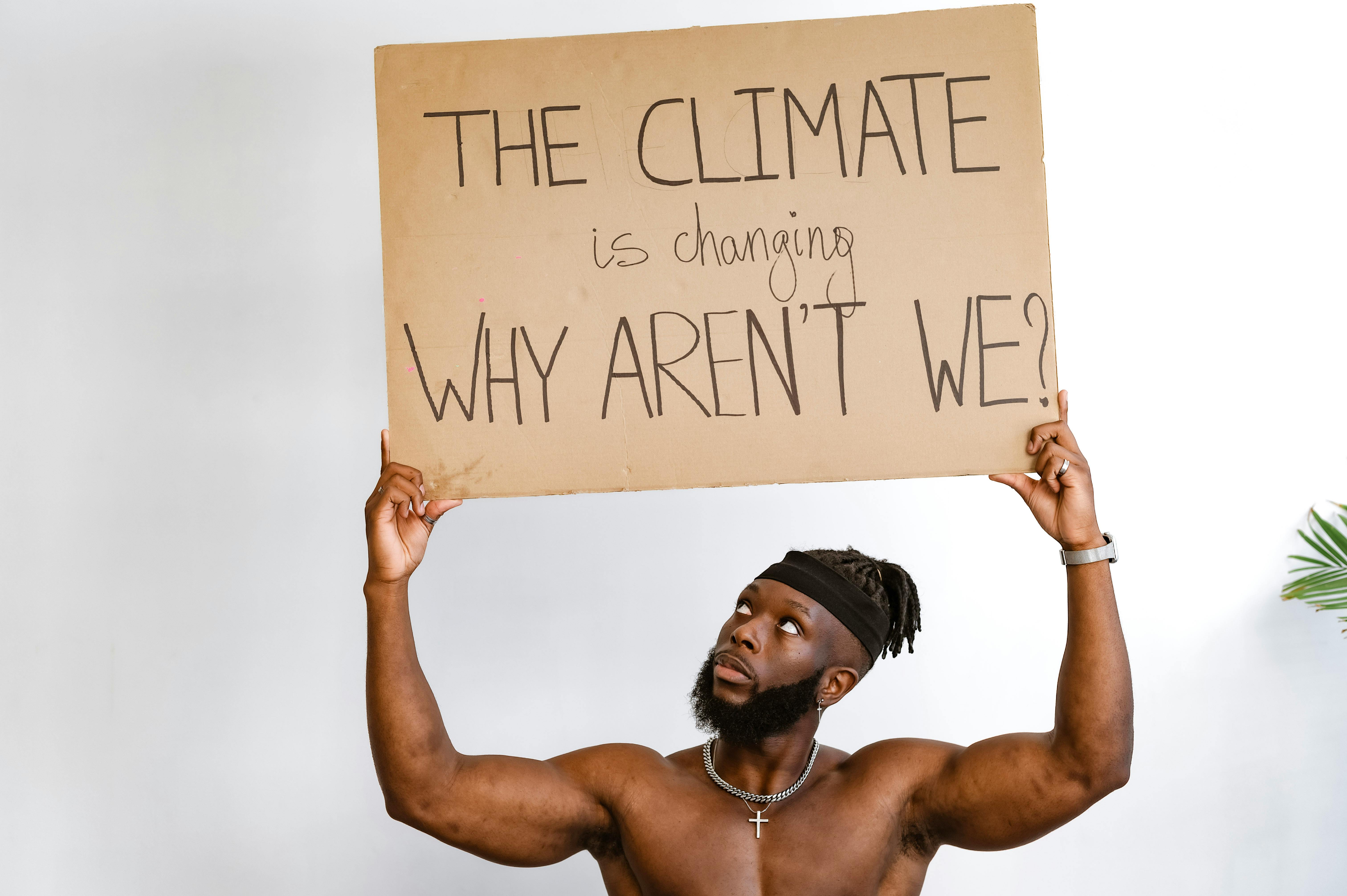 Shirtless African American man holding a climate change awareness sign.