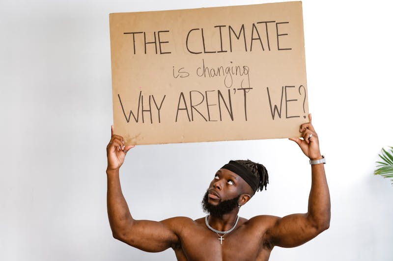 Shirtless African American man holding a climate change awareness sign.