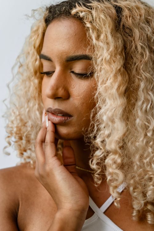 Free Close-up portrait of a thoughtful woman with curly blonde hair and gentle expression. Stock Photo
