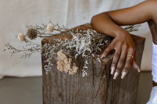 A Person with Her Arms on a Wooden Block with Flowers