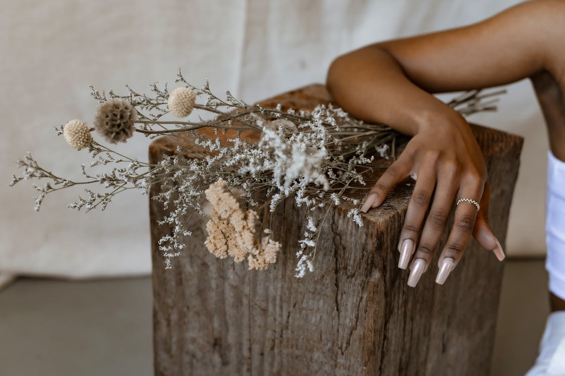 Free A Person with Her Arms on a Wooden Block with Flowers Stock Photo