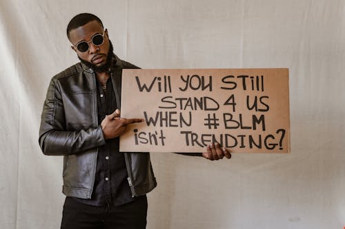 Man Standing in Black Leather Jacket Holding a Poster