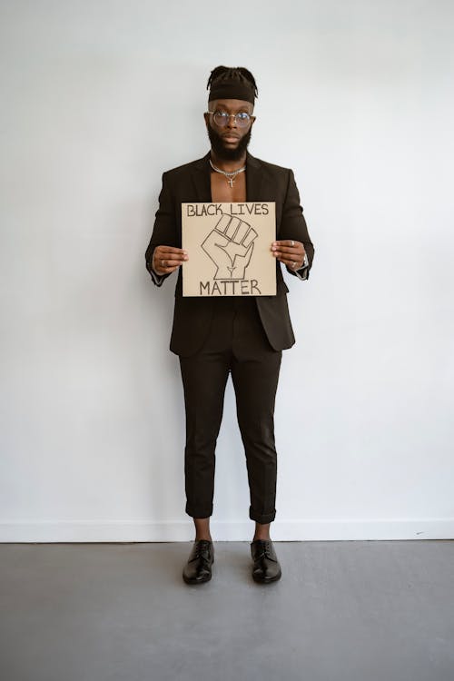 Man in Black Suit Holding a Poster 