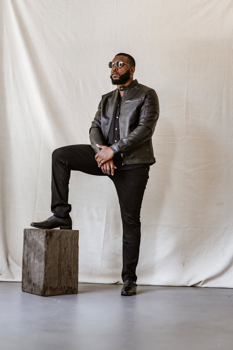 A Man In A Leather Jacket Stepping On A Wooden Block