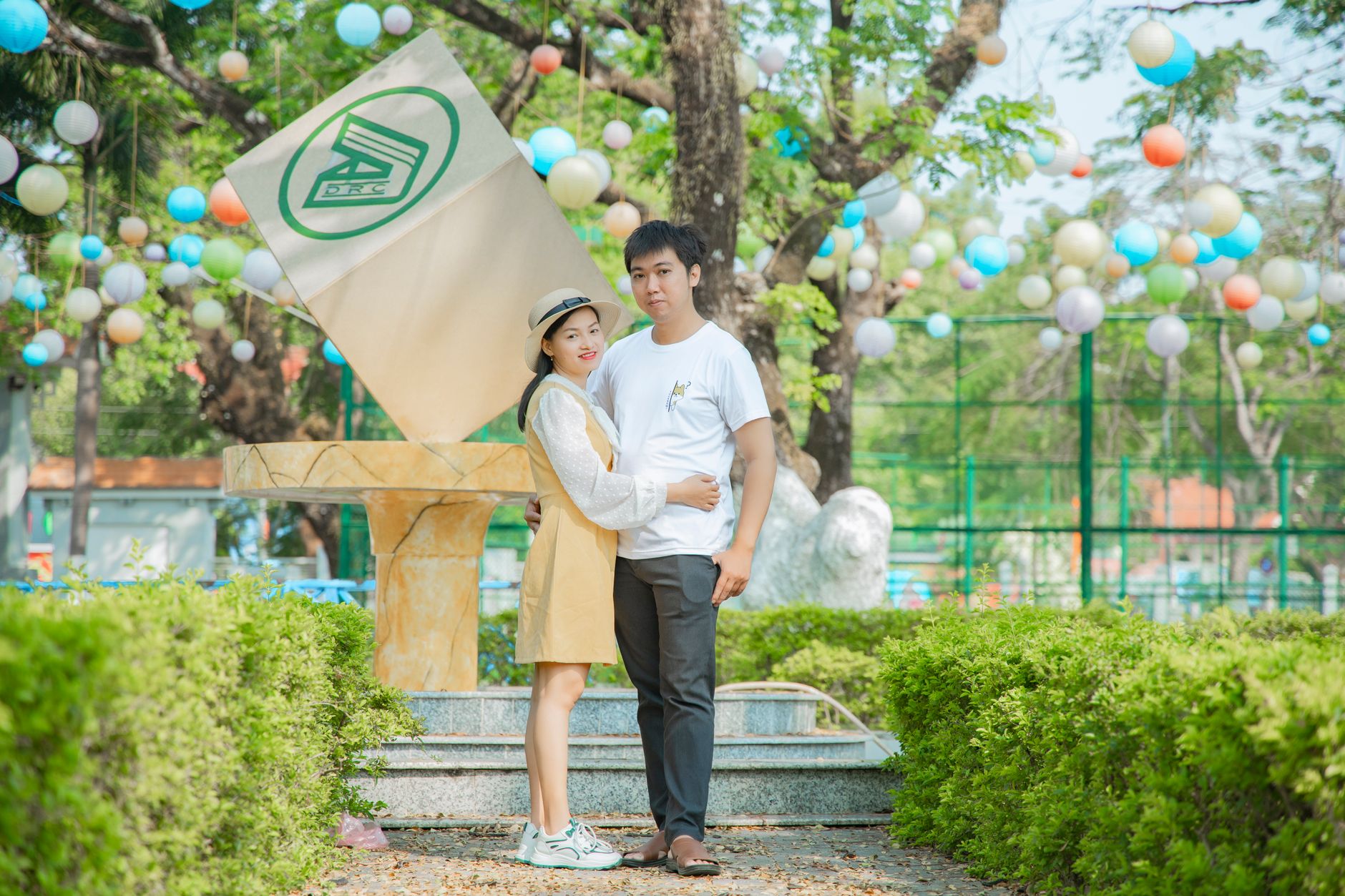 Happy couple embracing surrounded by colorful decorations in a sunny park.