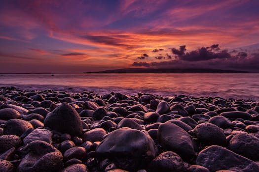 A breathtaking sunset over a rocky beach with vibrant skies and serene ocean view.
