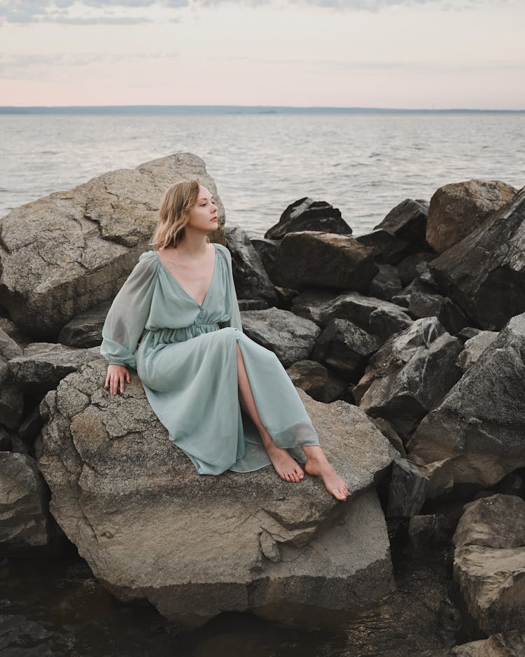 Charming Woman Sitting On Stone Near Sea