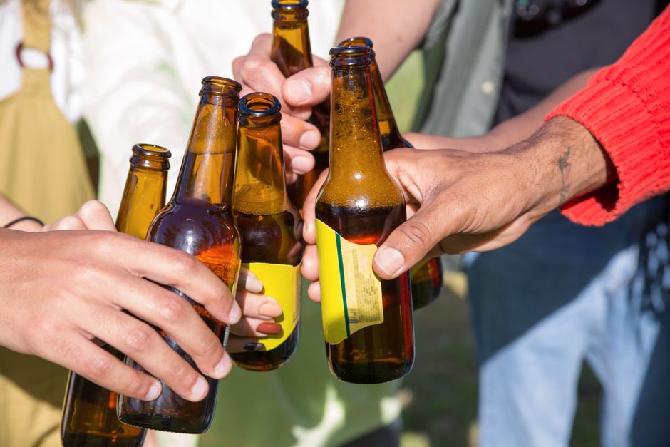 Group of people toasting with beer bottles at an outdoor event in the Bay Area