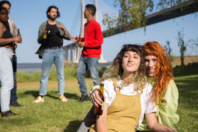 Young Women Embracing On A Picnic With Friends