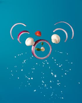 Floating ingredients like onions and mushrooms on blue background. Vibrant composition.