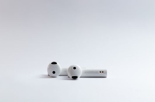 Close-up of white wireless earphones on a clean white background, ideal for tech and lifestyle concepts.