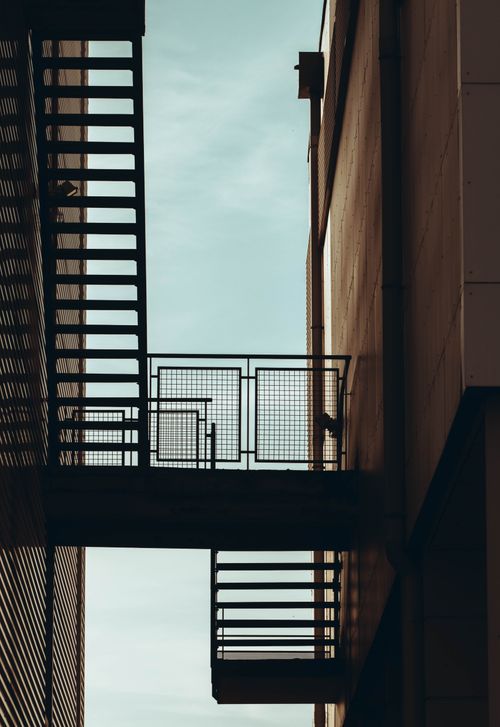 Free Low angle view of outdoor fire escape stairs between buildings, offering an architectural contrast. Stock Photo