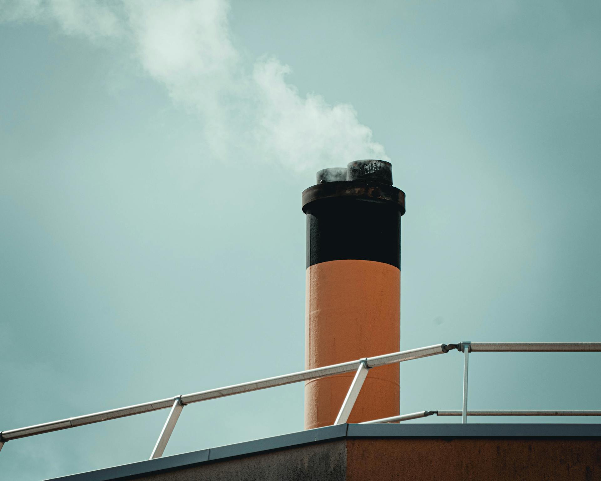 An industrial chimney releasing smoke into the sky, depicting pollution and emissions.