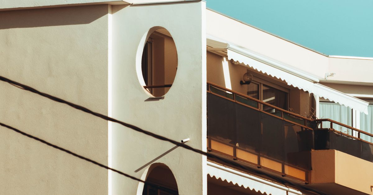 Photo by Tony Mrst A modern apartment building featuring balconies under a clear blue sky.