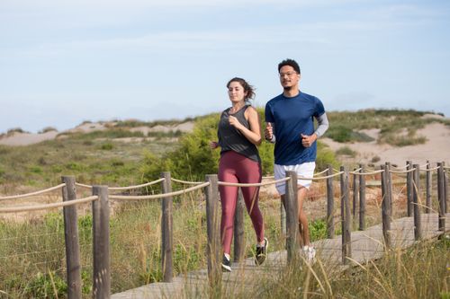 Free Active couple jogging on a scenic coastal boardwalk in Portugal, enjoying fitness and nature. Stock Photo
