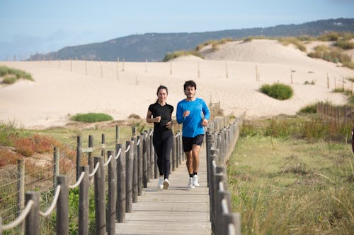 Free Man and Woman Jogging on a Boardwalk Stock Photo