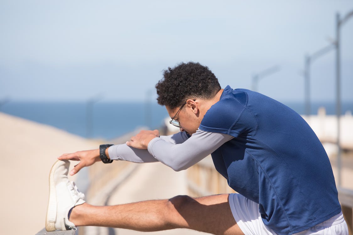 man in Blue Shirt Stretching His Leg