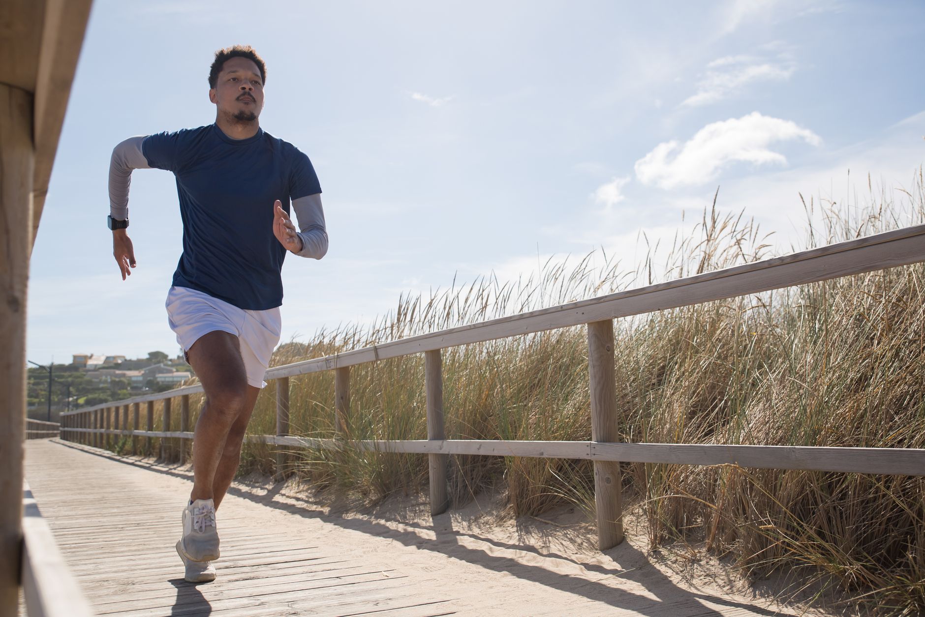 Athletic man running on a sunny coastal boardwalk in Portugal, showcasing fitness and determination.