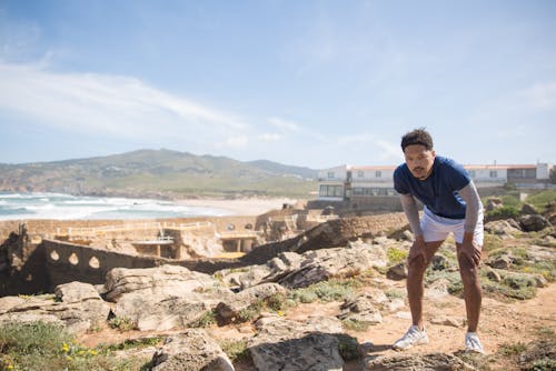 A Man Standing on the Rocky Surface Near the Coast