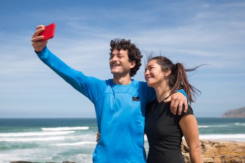 Free Happy couple taking a selfie on a sunny beach in Portugal. Stock Photo