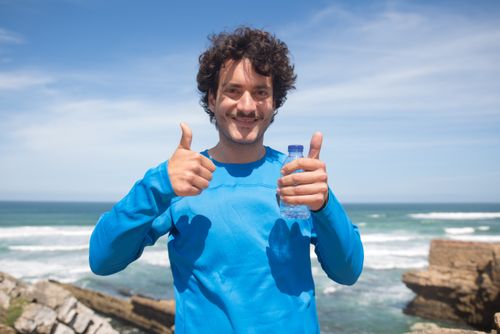 Free Smiling man enjoying a sunny day at the beach in Portugal, giving thumbs up. Stock Photo