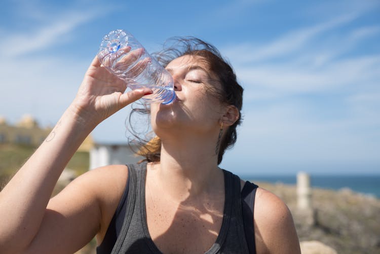 A Woman Drinking A Bottled Water