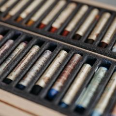 Rows of wrapped oil pastels in a black foam tray