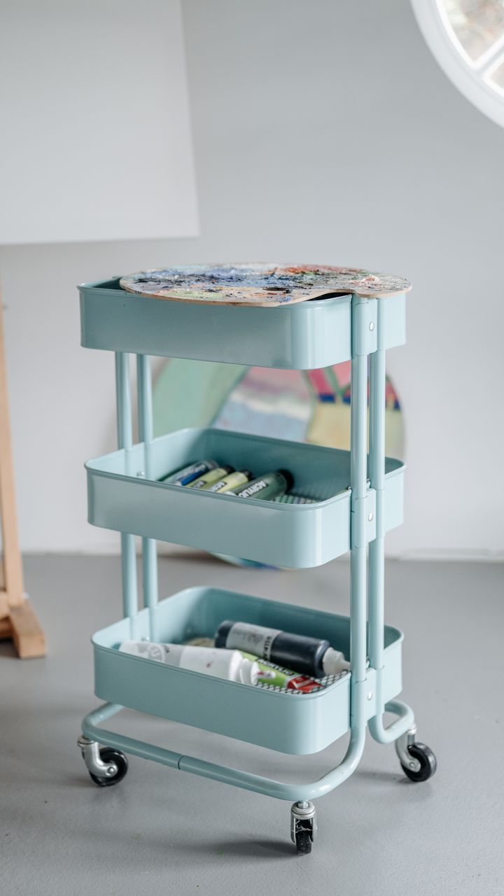 wooden rolling utility cart in a corner used as a small coffee bar with supplies