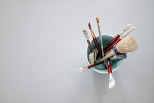 Paint Brushes in the Bucket over a White Surface