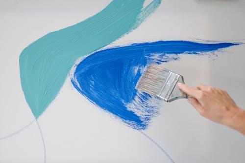 Close-up of Person Painting White Surface with Blue Paint 