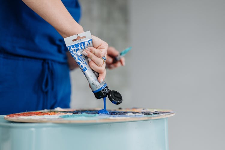 A Person Squeezing Blue Paint On A Palette Tray