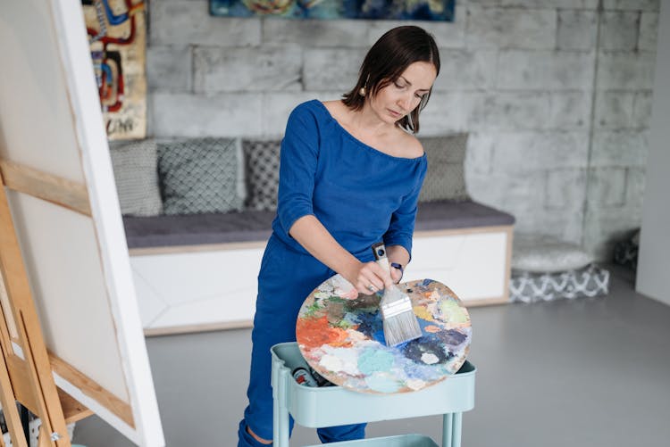 Woman In Blue Overalls Holding Paint Brush