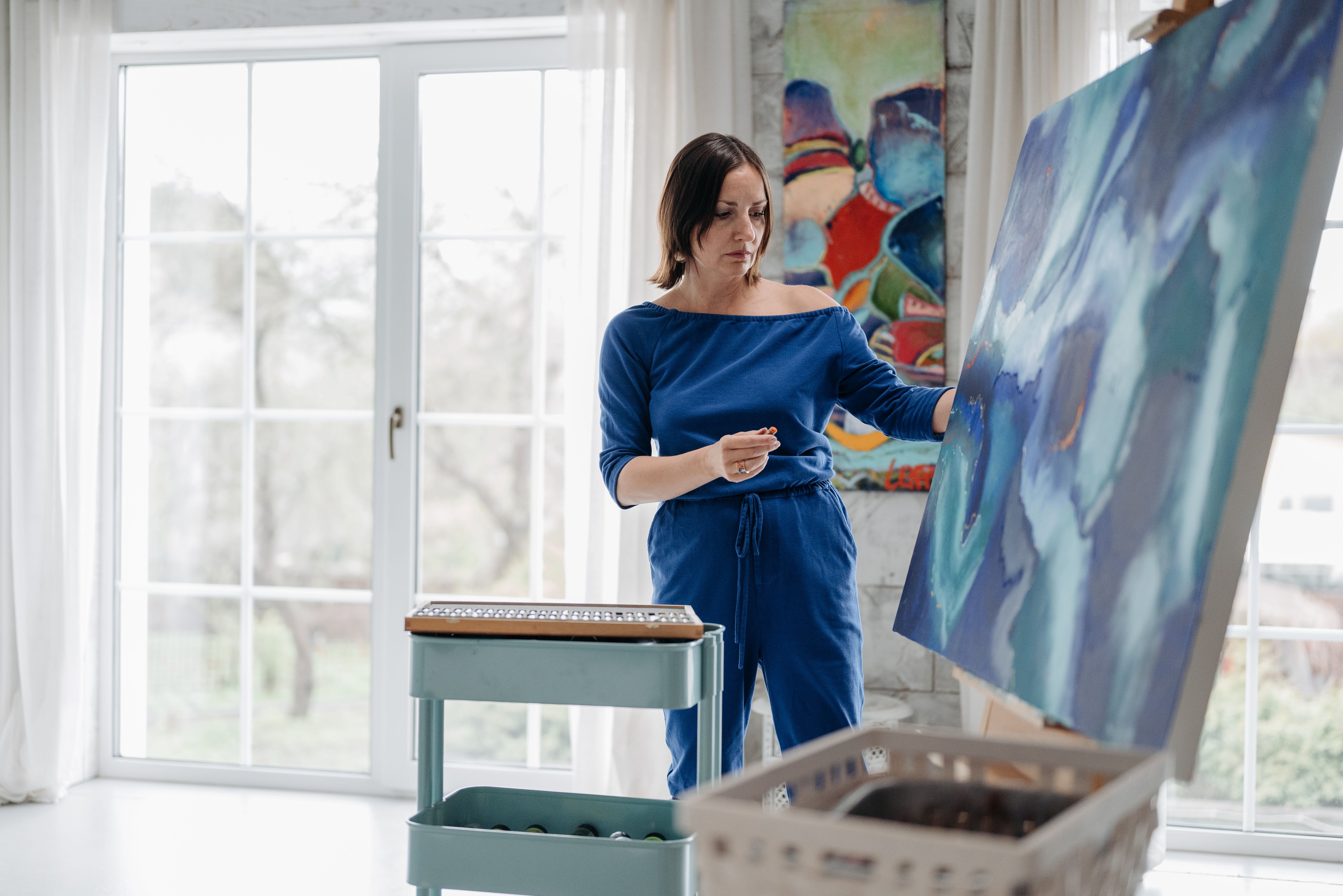 A bright and airy art studio with a large window overlooking a garden, showcasing the peaceful and inspiring environment created through reverse nesting.