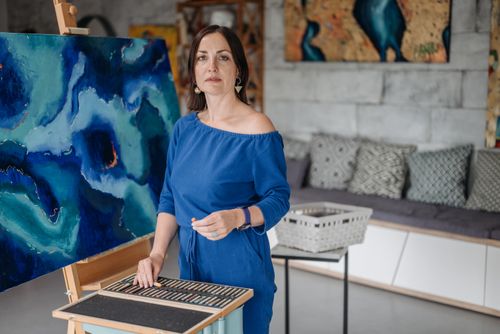 Free A female artist working on an abstract blue canvas using pastels in an art studio. Stock Photo