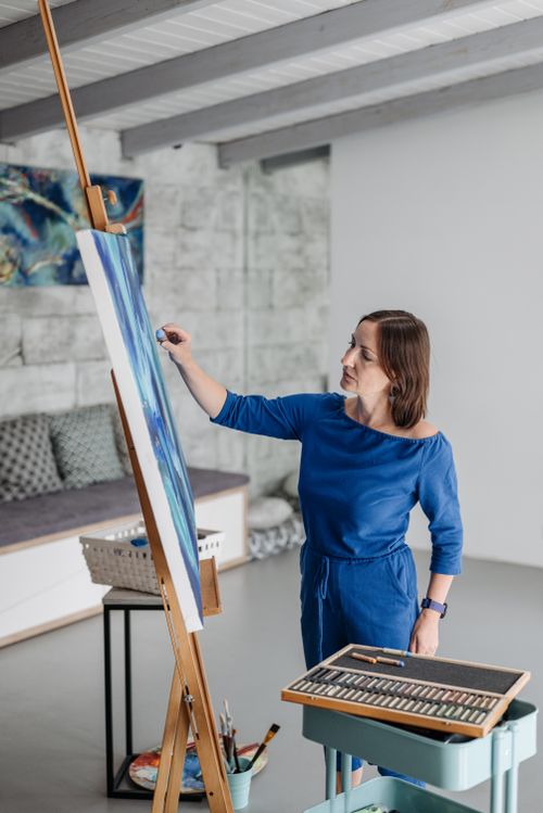 Free A woman in blue painting on a canvas in a modern art studio. Stock Photo